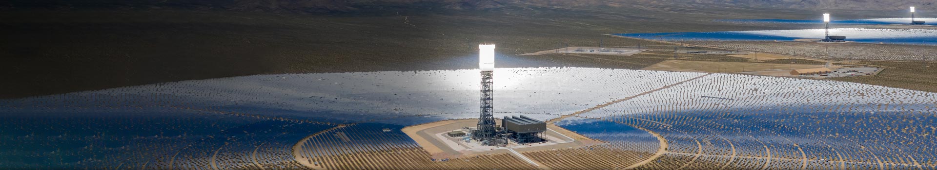 Desert landscape with hundreds of solar-tracking heliostat panels.