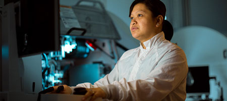 Female engineer in cleanroom operates complex machinery.