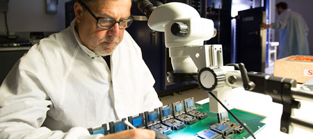 Senior engineer examines an electronic device with a q-tip.