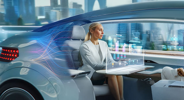 Two people sit facing each other in a sleek autonomous vehicle with digital screens and city views.