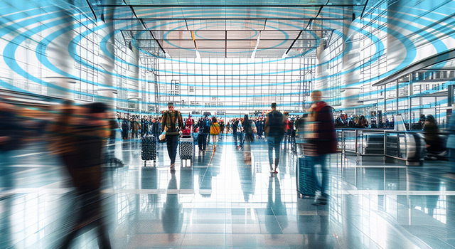 Busy airport terminal with passengers walking through, overlaid with digital concentric rings symbolizing wireless communication or connectivity.