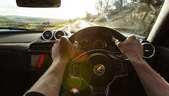 Lotus car interior and a person holding steering wheel driving on a country road