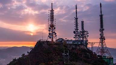 Communication towers on a hill at sunset