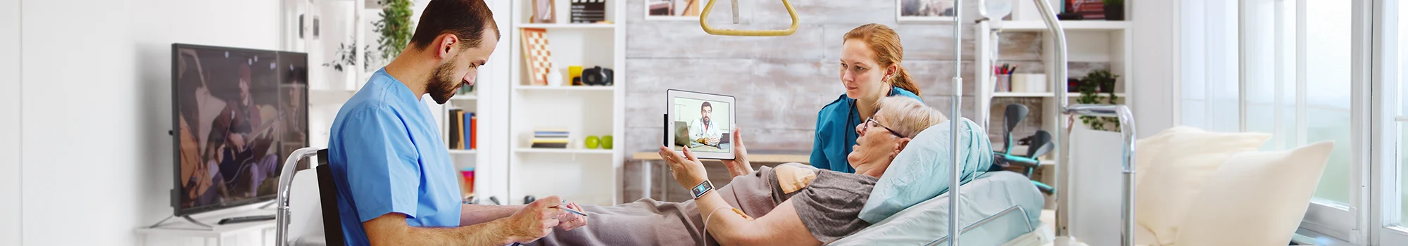 Elderly woman in home care video calls doctor, assisted by nurse in a calm, well-equipped room.