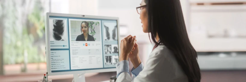 Person in white coat video calling from office, with charts and text displayed beside the video on screen.