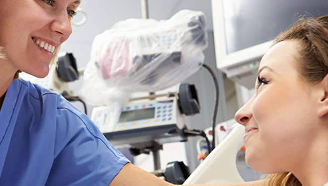 Close-up of female nurse caring for female patient in hospital room.