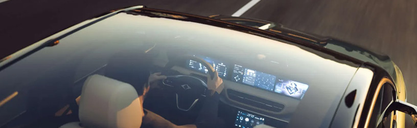 A futuristic car with a sleek design is seen from above, reflecting the sunset on its windshield as the driver navigates the road.